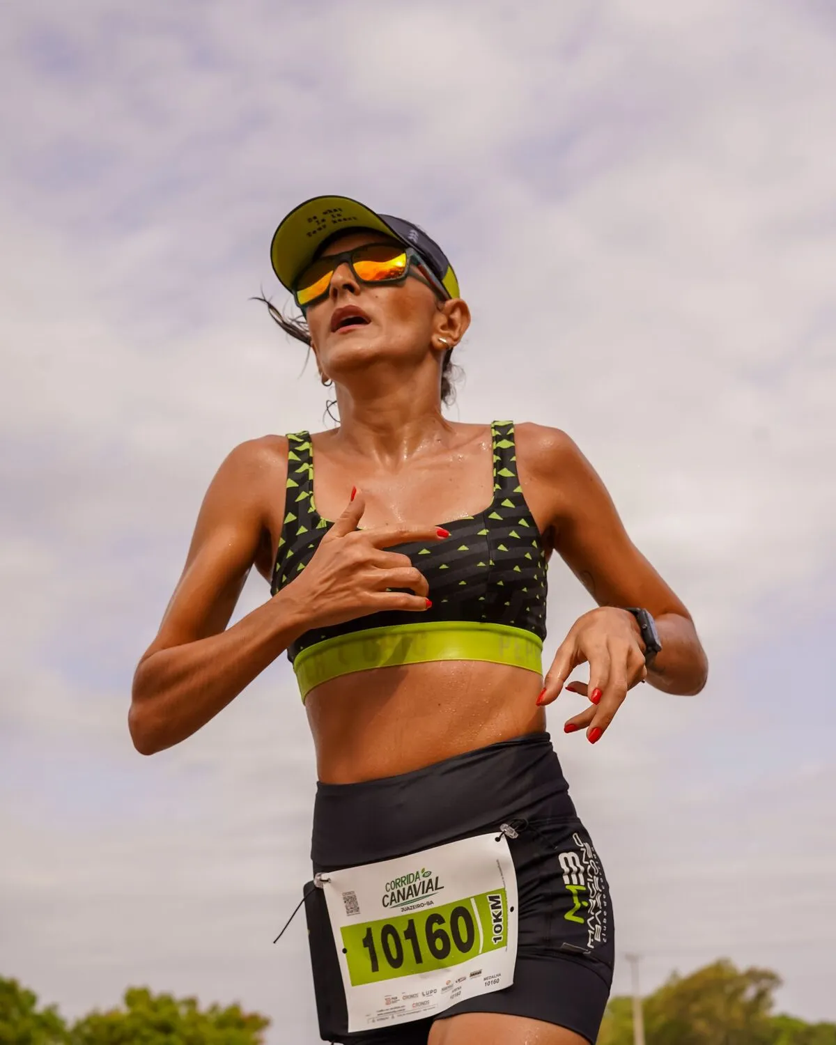 Corredora con top deportivo y lentes durante una carrera
